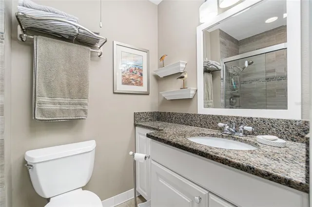 a bathroom with a granite countertop toilet sink and mirror