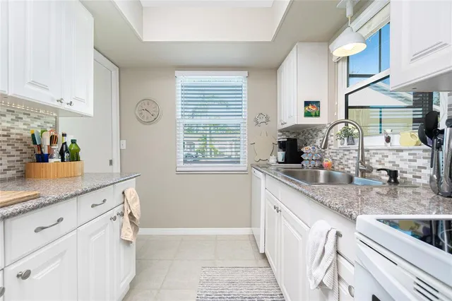 a kitchen with granite countertop a sink white cabinets and window