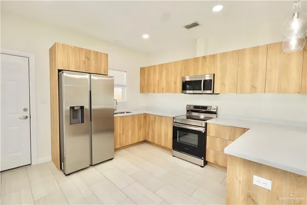 a kitchen with stainless steel appliances granite countertop a refrigerator a stove a sink and a microwave