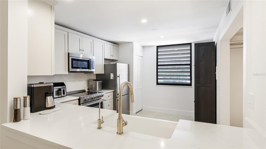 303 Springdale Drive, Unit 303 Bradenton, FL 34210 - Photo 6 of 23 a kitchen with stainless steel appliances kitchen island sink refrigerator and microwave