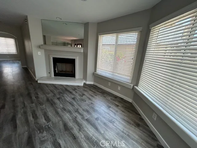 a view of an empty room with wooden floor a fireplace and a window
