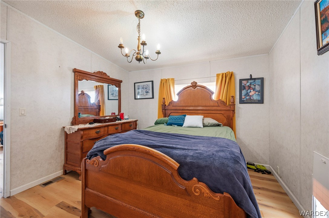 2465 Egar Road Golden Valley, AZ 86413 - Photo 29 of 98 The bedroom features wood flooring, a decorative light fixture, and a window with yellow curtains