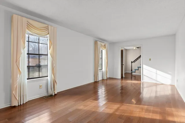 a view of empty room with wooden floor and entryway