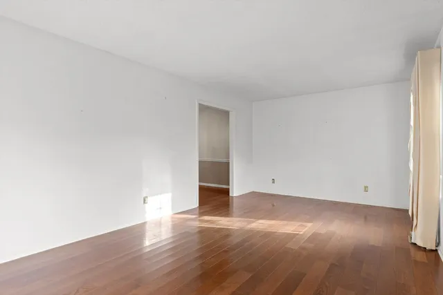 an empty room with wooden floor and natural light