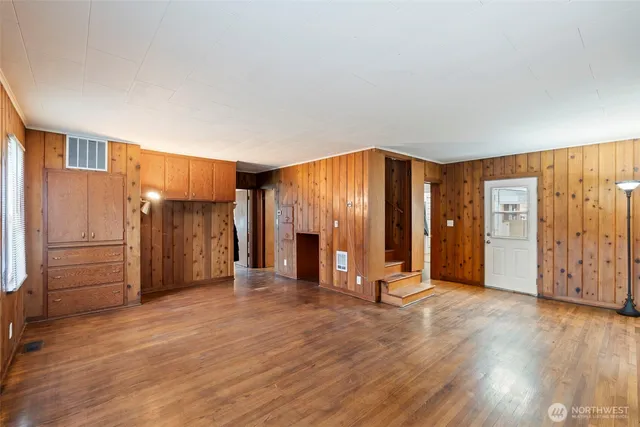 a view of an empty room with wooden floor and closet
