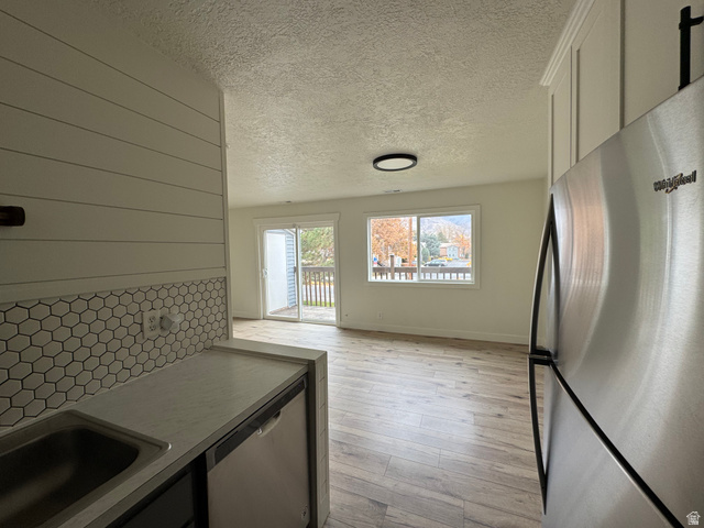 608 South 500 West, Unit 3 Provo, UT 84601 - Photo 9 of 35 Open-concept living area featuring wood-finish flooring, a contemporary ceiling light fixture, and a sliding glass door leading to an outdoor deck
