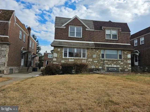 a view of a brick house with many windows next to a yard