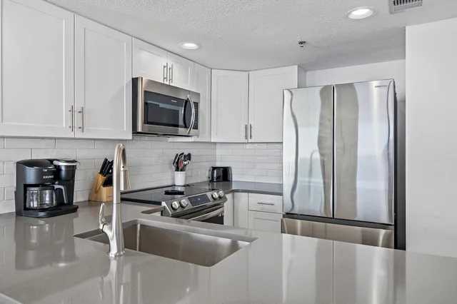 a kitchen with granite countertop a refrigerator and a stove top oven