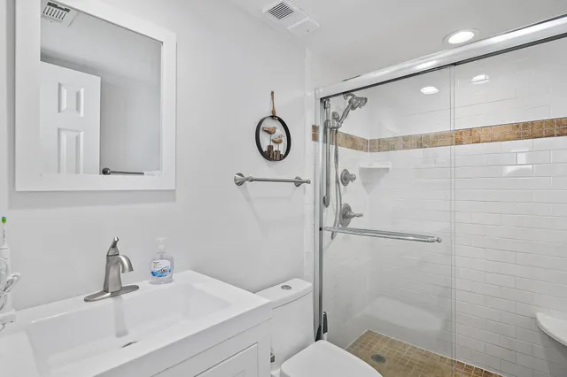 a bathroom with a shower sink vanity mirror and toilet