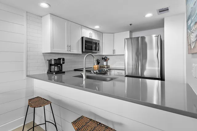 a kitchen with a refrigerator a sink and white cabinets