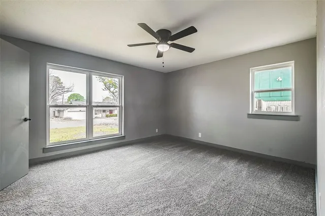 an empty room with ceiling fan and windows