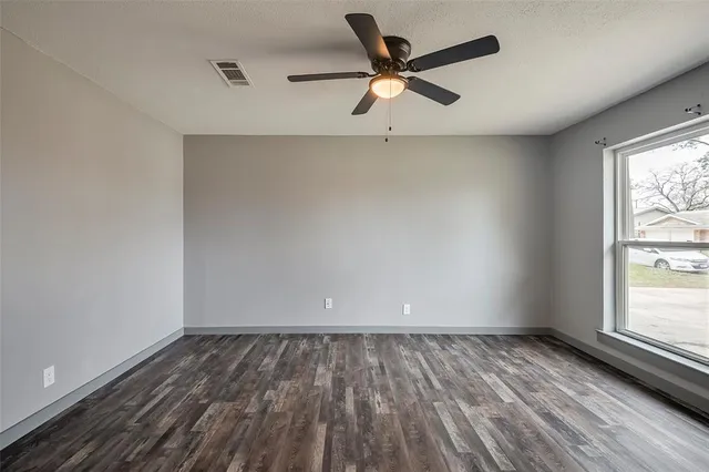 an empty room with a window and a ceiling fan