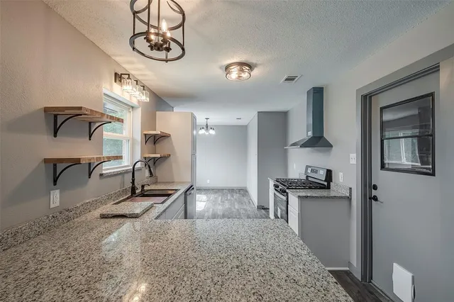 a kitchen with stainless steel appliances granite countertop a sink a stove and a refrigerator