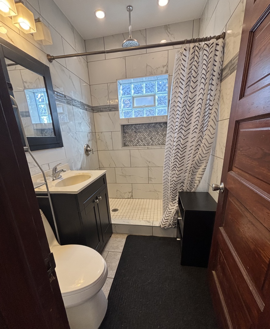 3133 North Richmond Street, Unit 2 Chicago, IL 60618 - Photo 6 of 16 a bathroom with a sink a toilet a mirror a vanity and shower