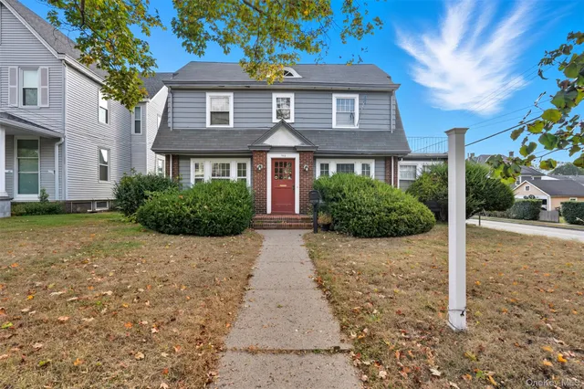 a front view of a house with a yard and trees