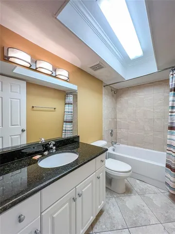 a bathroom with a granite countertop sink a toilet a mirror and bathtub