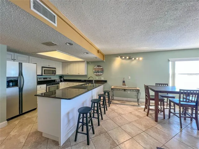 a kitchen with stainless steel appliances kitchen island granite countertop a table and chairs