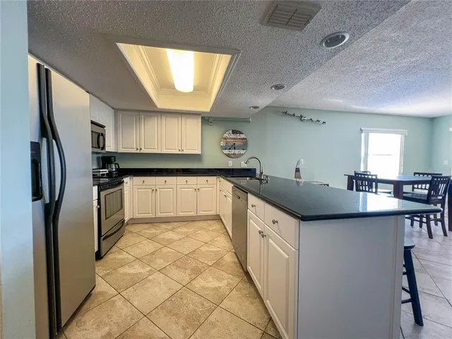 a kitchen with granite countertop a sink stove and refrigerator