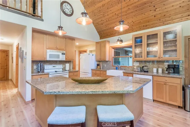 a kitchen with kitchen island granite countertop wooden floor and a refrigerator