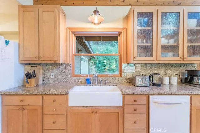 a kitchen with granite countertop a sink window and cabinets