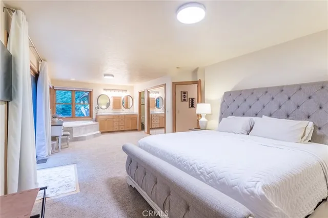 a spacious bedroom with a large bed a couch and chandelier