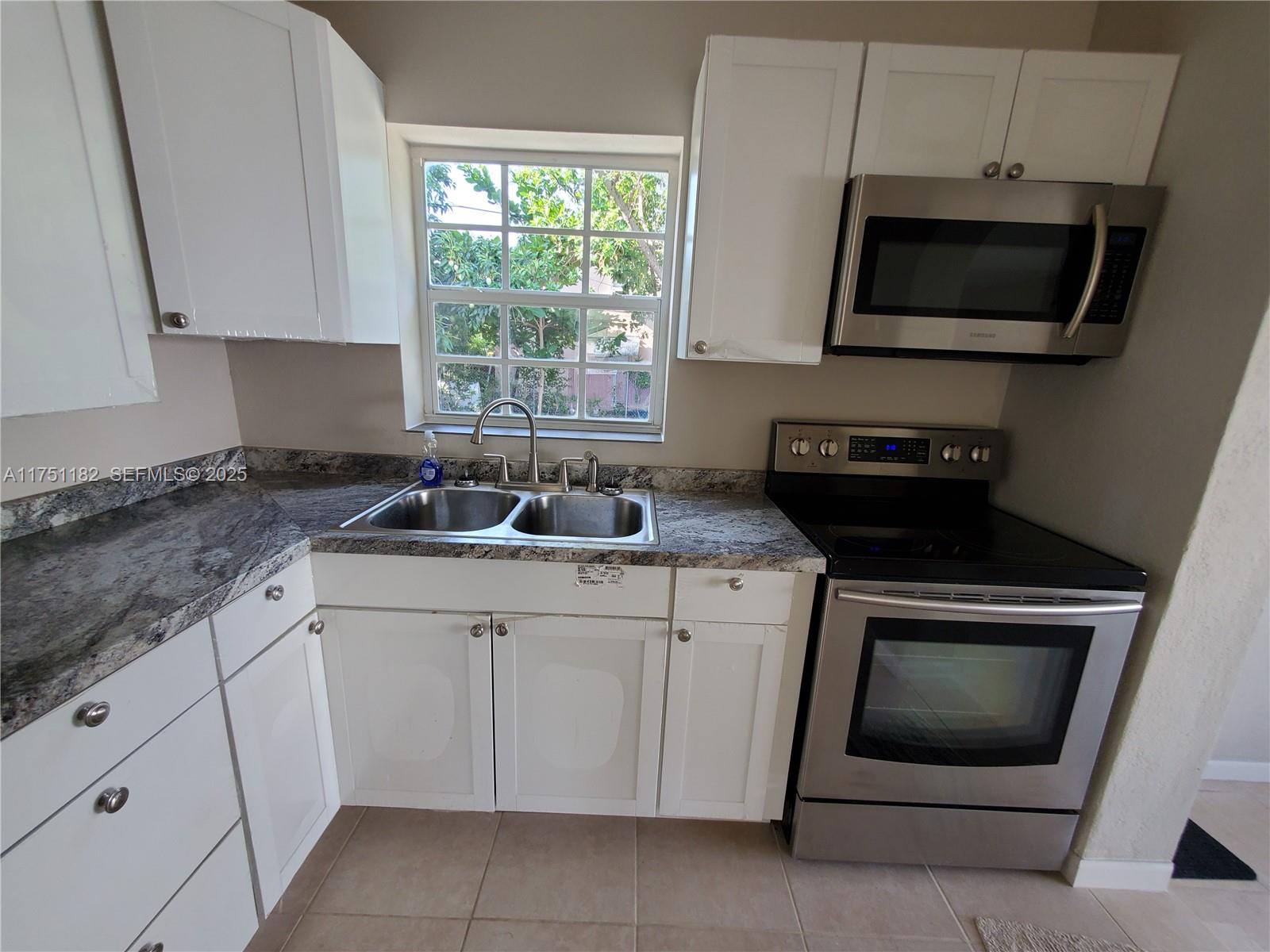 70 Northwest 33rd Street Miami, FL 33127 - Photo 15 of 48 a kitchen with white cabinets and a stove top oven