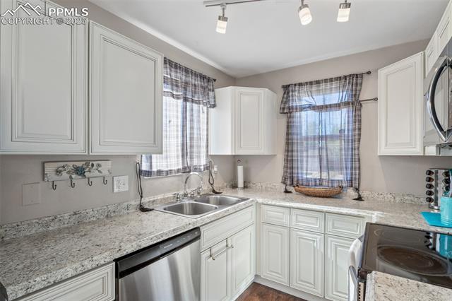 4469 Fenton Road Colorado Springs, CO 80916 - Photo 13 of 38 Kitchen featuring stainless steel appliances, white cabinetry, and dark wood-style floors