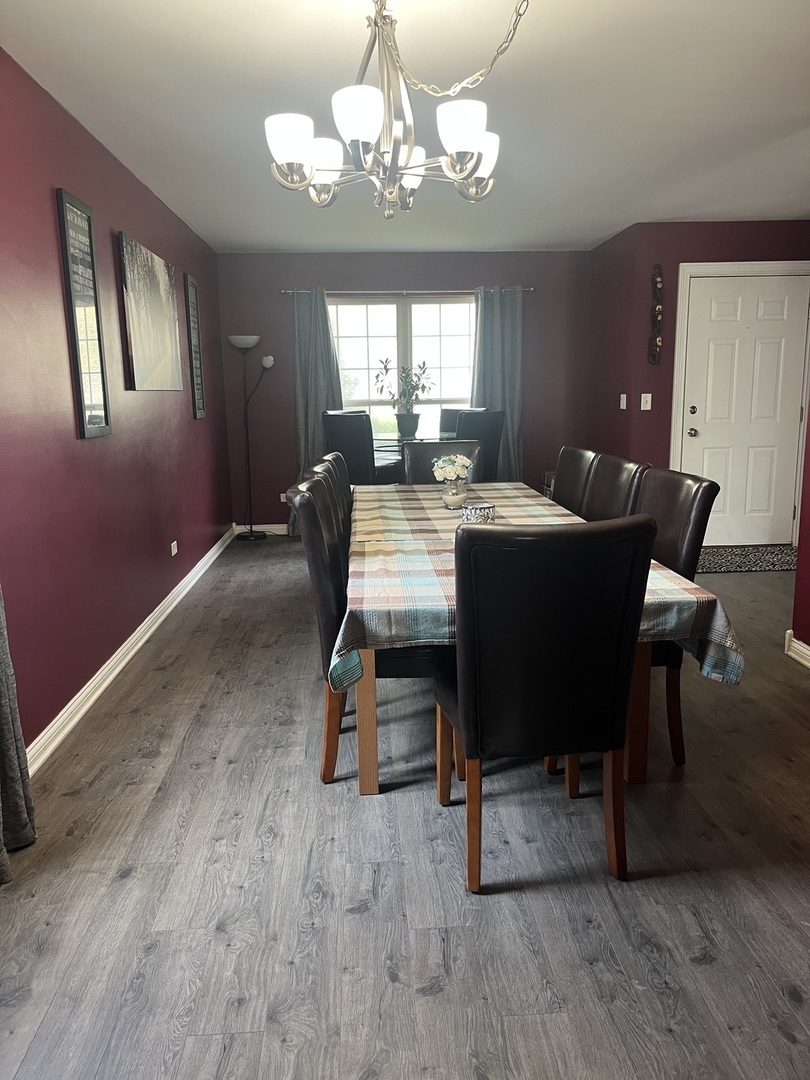 142 Sedgewicke Drive Romeoville, IL 60446 - Photo 3 of 18 a dining room with wooden floor a chandelier a wooden table and chairs