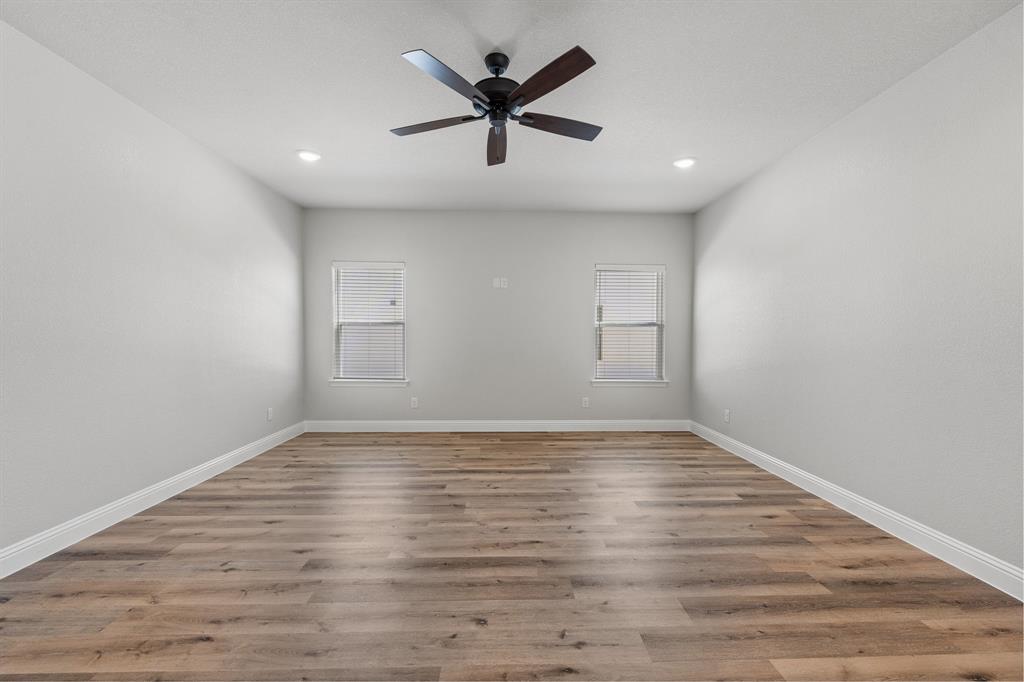 1568 Reverie Road Burleson, TX 76028 - Photo 13 of 26 a view of an empty room with wooden floor and a ceiling fan