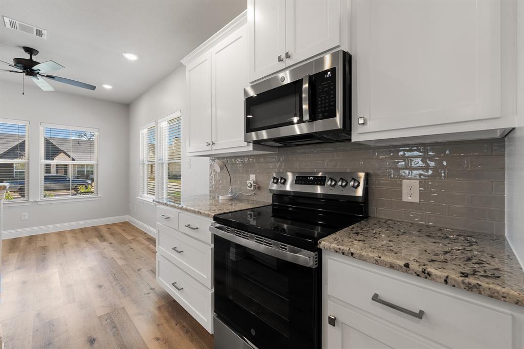 1568 Reverie Road Burleson, TX 76028 - Photo 8 of 26 a kitchen with stainless steel appliances granite countertop a stove a microwave and cabinets