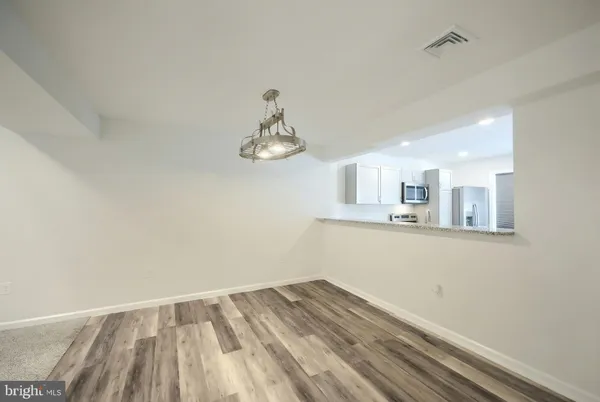 a large kitchen with a refrigerator a sink dishwasher a stove and white cabinets with wooden floor