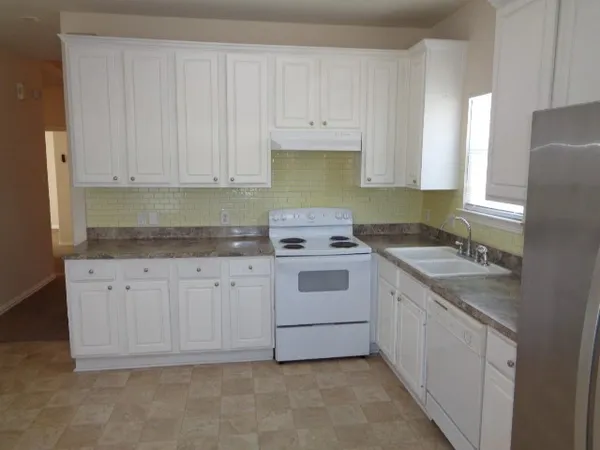 a kitchen with granite countertop white cabinets sink and white appliances
