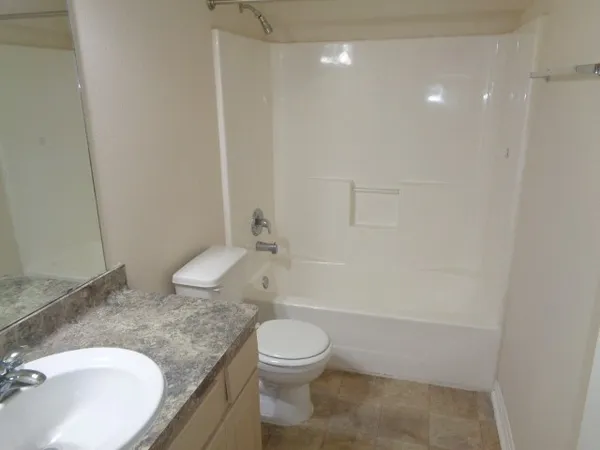a bathroom with a granite countertop sink a toilet and shower