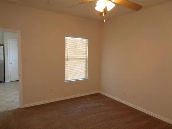 an empty room with a chandelier fan and wooden floor