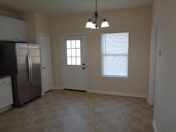 an empty room with chandelier fan and windows