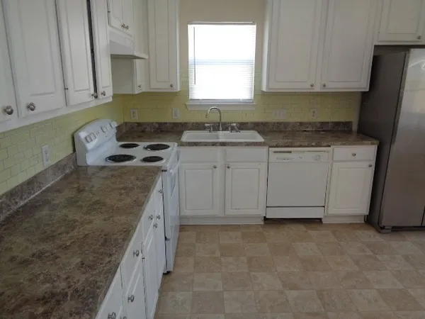 a kitchen with granite countertop a sink stove and cabinets
