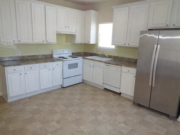 a kitchen with granite countertop a sink and a refrigerator