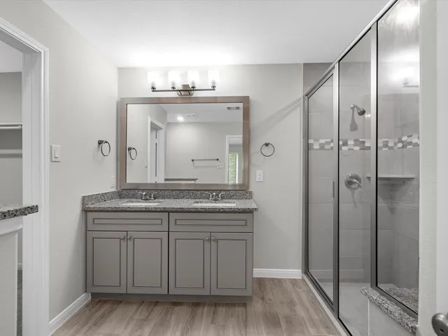 a bathroom with a granite countertop sink a mirror and a shower