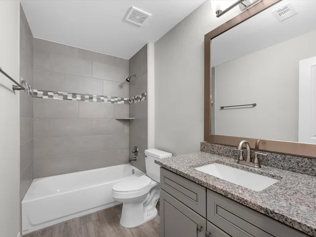 a bathroom with a granite countertop sink toilet and shower