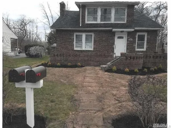 a front view of a house with garden and trees