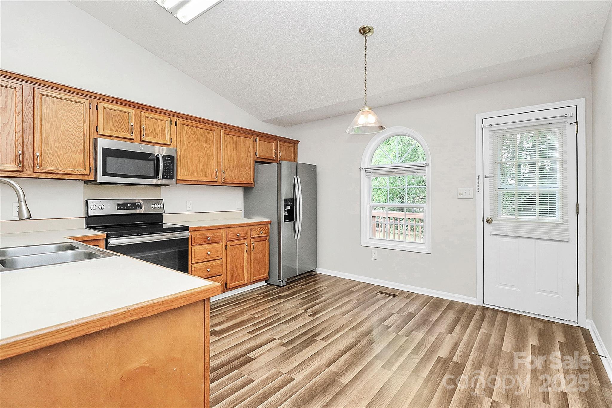 5114 Daffodil Lane Concord, NC 28025 - Photo 7 of 30 a kitchen with stainless steel appliances granite countertop a stove a sink dishwasher a refrigerator and a microwave oven with wooden floor