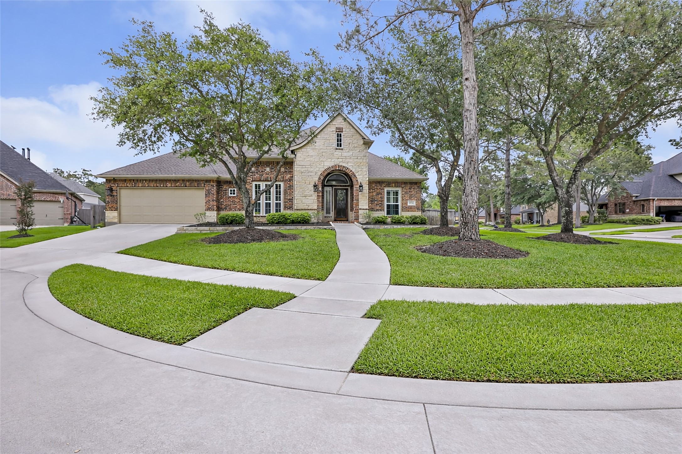 Elegant, single-story brick home set on a beautifully landscaped corner lot with mature trees and well-maintained lawn