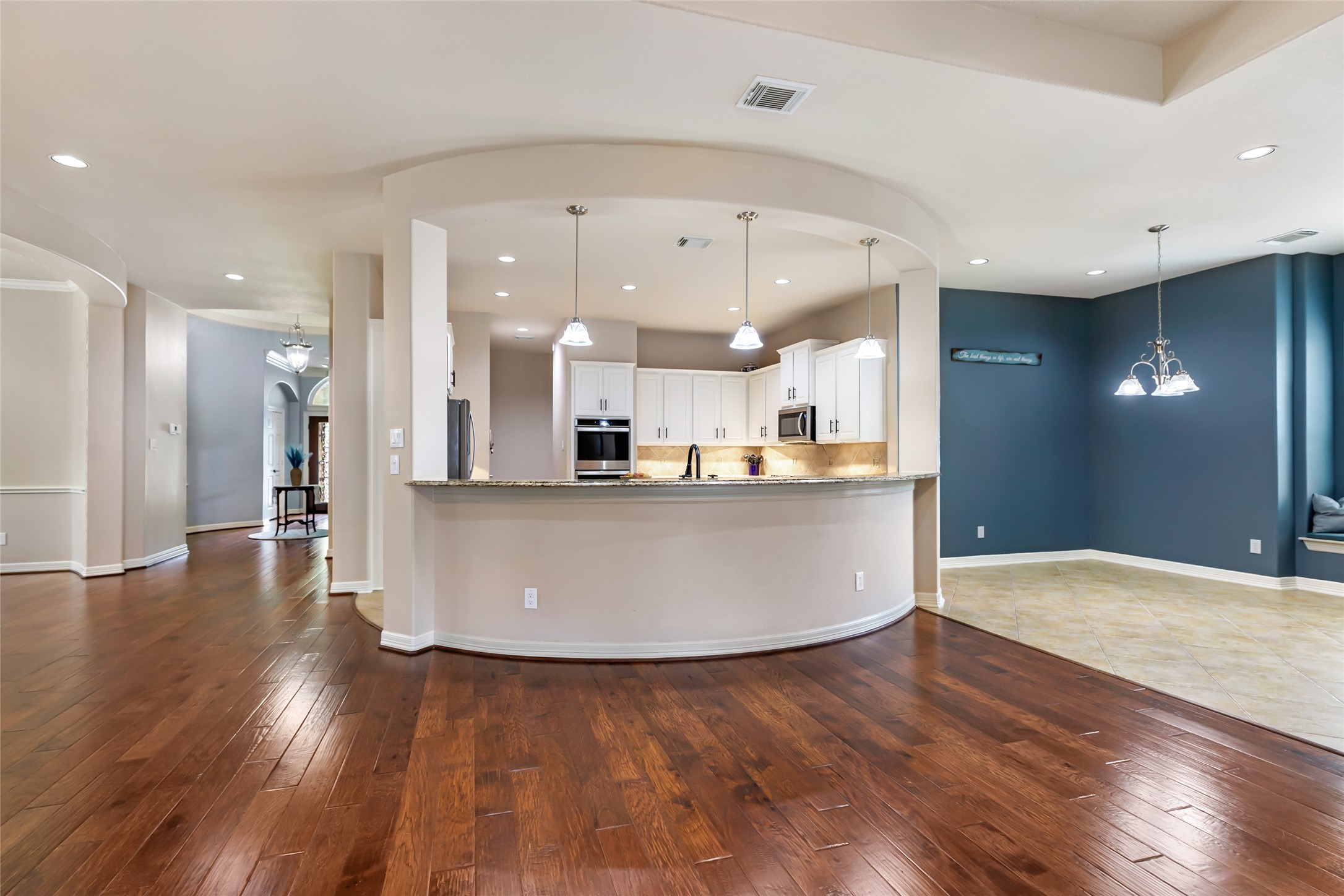 17302 Pipestone Point Court Humble, TX 77346 - Photo 14 of 50 Modern kitchen with large, curved bar and pendant lighting connected to the living room
