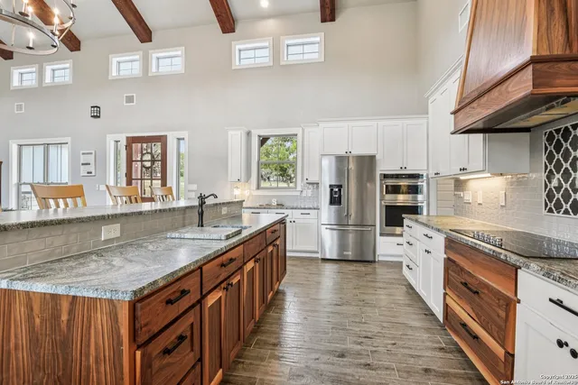 a kitchen with stainless steel appliances granite countertop a kitchen island a stove a sink dishwasher and a refrigerator