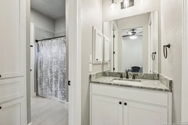 a bathroom with a granite countertop sink two mirror and shower