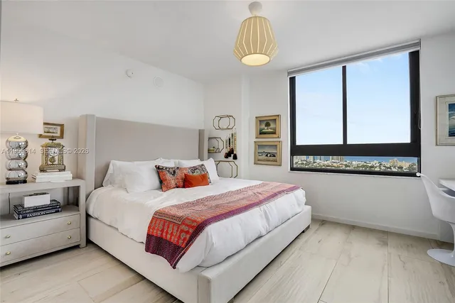 a bedroom with a bed lamp and a large window