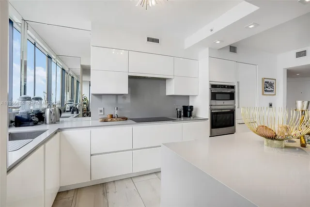 a kitchen with granite countertop white cabinets and stainless steel appliances