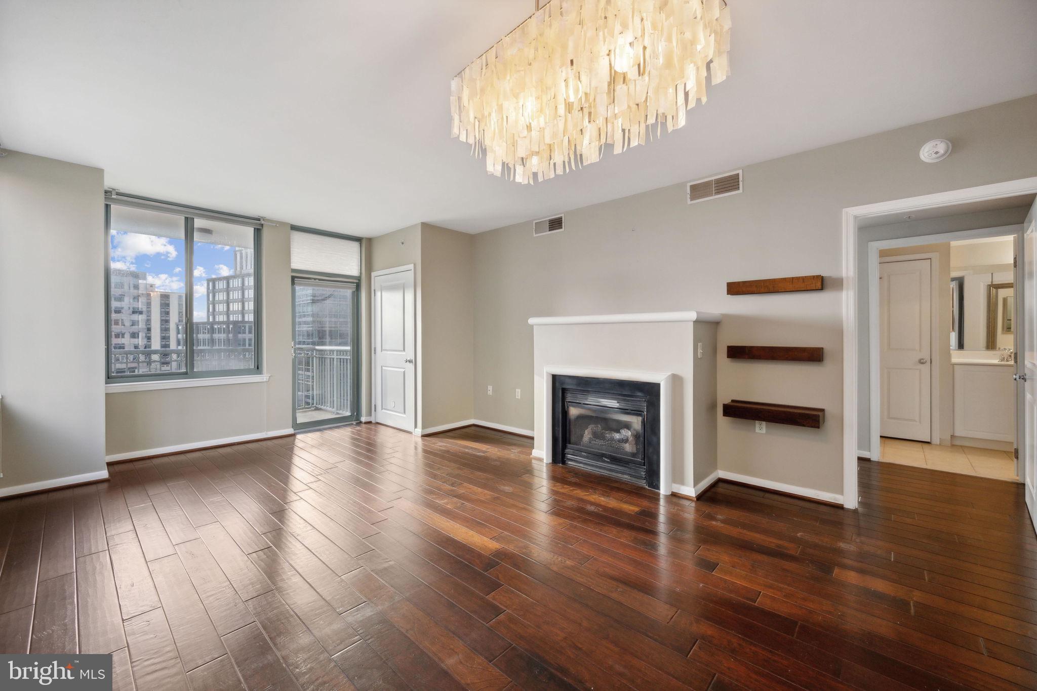 851 North Glebe Road, Unit 604 Arlington, VA 22203 - Photo 5 of 58 an empty room with wooden floor a fireplace a windows and a ceiling fan