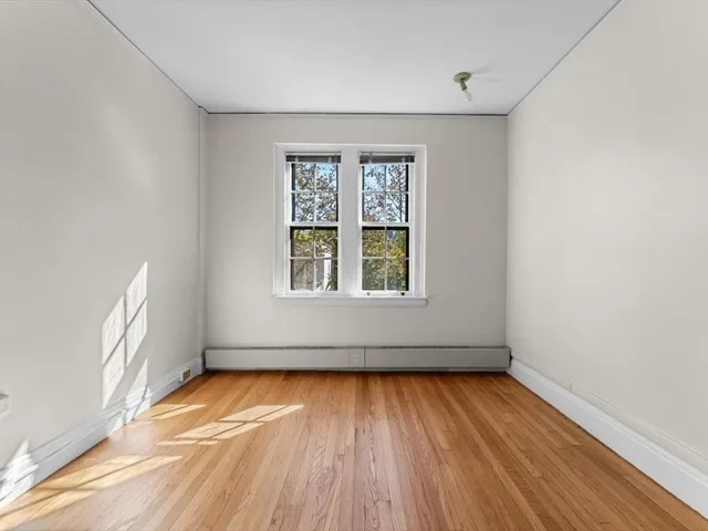 an empty room with a window and wooden floor