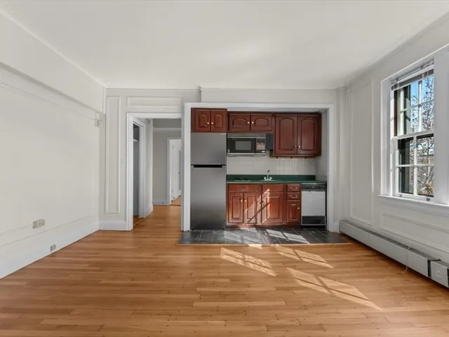 a view of empty room with kitchen and window